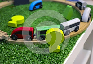 Children`s wooden train with cars, railway and wooden trees on artificial plastic green grass. Early childhood education,