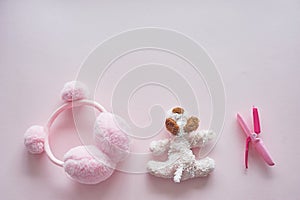 Children`s world girl. Pink background,toy, curling tongs and earbuds with pumpons.