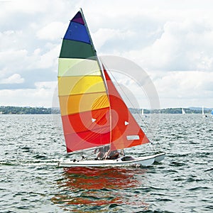 Children Sailing small sailboat boat with a Colourful Sails on an inland waterway