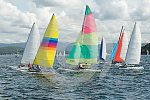 Children Sailing small sailboats with colourful sails on an inland waterway