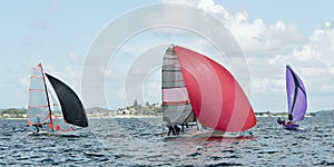 Children Sailing small sailboats with colourful sails on an inland waterway