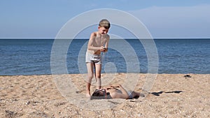 Children on the sandy sea beach play with sand.