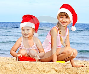 Children in santa hat on beach.