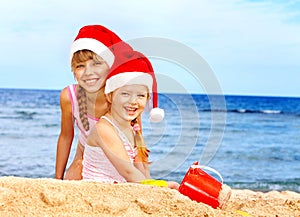 Children in santa hat playing on beach.