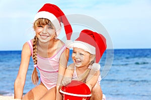 Children in santa hat playing on beach.