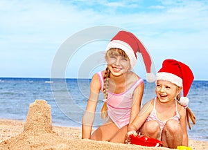 Children in santa hat playing on beach.