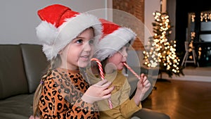Children in santa hat watch cartoons and eat candies