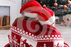 Children in santa hats near christmas tree, wait for holidays