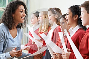 Children In School Choir Being Encouraged By Teacher