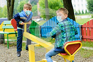 Children school in medical masks play at a quarantine playground during a coronavirus pandemic