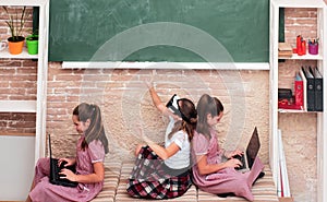 Children in the school space with gadgets sitting on the floor. Education, modern school, learning, technology and