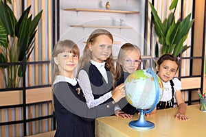 Children in school uniforms with a globe in the office.