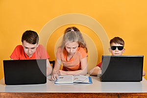 Children are schooled at home, two boys are sitting at a laptop, a girl is reading books photo