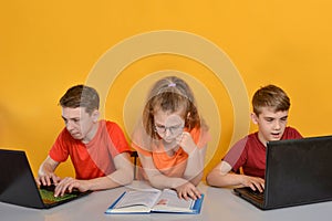 Children are schooled at home, two boys are sitting at a laptop, a girl is reading books