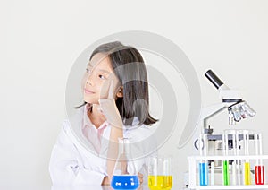 Children science concept, Happy little girl is sitting at the table and thinking at the laboratory with white background