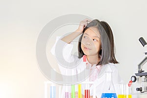 Children science concept, Happy little girl is sitting at the table and thinking at the laboratory with white background