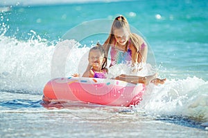 Children at sea play merrily. Two sisters run, jump on the beach in summer.
