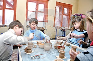 Children shaping clay in pottery studio photo