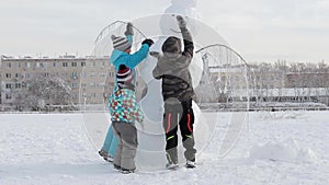 A children is shaping a snowman in heavy snow