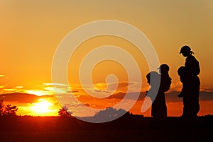 Children on the shoulders of parents go summer evening