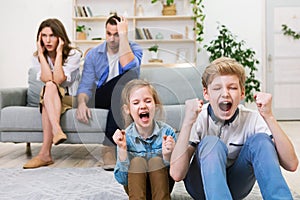 Children Shouting While Parents Covering Ears Sitting On Sofa Indoor