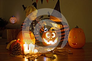 Children, siblings, playing with carved pumpkin at home on Halloween