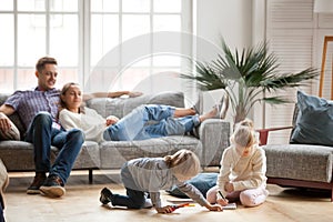 Children siblings playing drawing together while parents relaxin