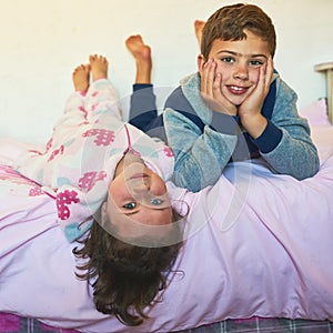 Children, siblings and portrait with relax on bed in home for playing, bonding and rest on weekend. People, brother and