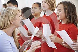 Children In Singing Group Being Encouraged By Teacher