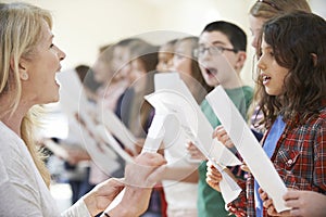 Children In Singing Group Being Encouraged By Teacher photo