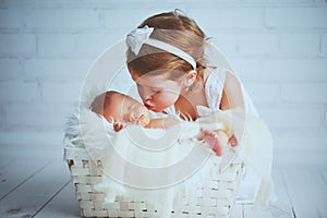 Children sister kisses brother newborn sleepy baby on a light