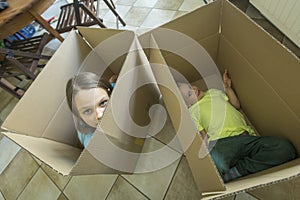 Children sit in cardboard boxes. Unpacking boxes and moving into a new home.