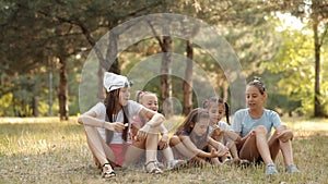 Children sit on the lawn in nature, socialize and eat apples