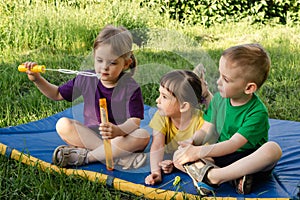 Children sit on the mat and play with soap bubbles