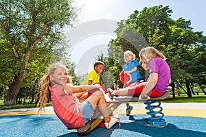 Children sit on playground carousel with springs photo