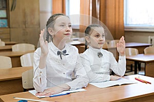 Children sit in school, one raises his hand.