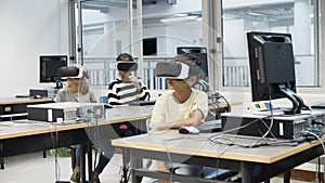 Children sitting in classroom and using virtual reality headset.