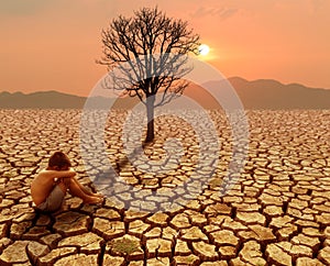 Children sitting on crack earth in arid area with dead tree and hot climate