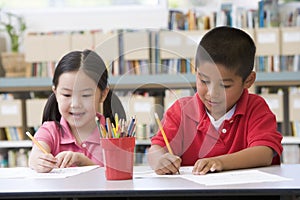 Children sitting at desk and writing in classroom