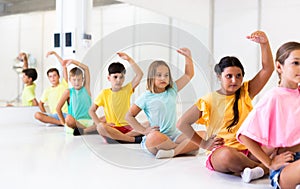 Children sitting and exercising ballet moves in studio