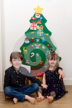 Children sitting in front of a Christmas tree