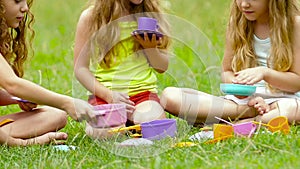 Children sitting on the grass playing with toys blurring the background. Slow motion. Close up