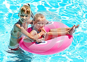 Children sitting on inflatable ring.