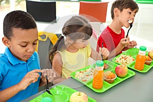 Children sitting at table and eating healthy food during break