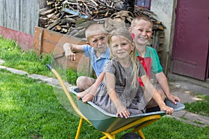 Children sitting in a wheelbarrow,happy children sitting in a wheelbarrow, two boys and a girl