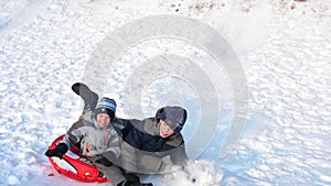 Children sled on a snowy mountain. Slow motion. Snowy winter landscape. Outdoor sports