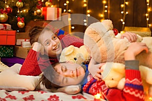 Children sleeping in new year or christmas decoration. Teenage boy and girl. Holiday lights, gifts and christmas tree decorated