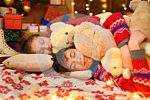 Children sleeping in new year or christmas decoration. Teenage boy and girl. Holiday lights, gifts and christmas tree decorated