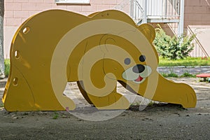 Children slide for rolling down top with wooden sides in form of bear painted in yellow.