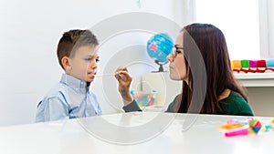 Children speech therapy concept. Preschooler practicing correct pronunciation with a female speech therapist.